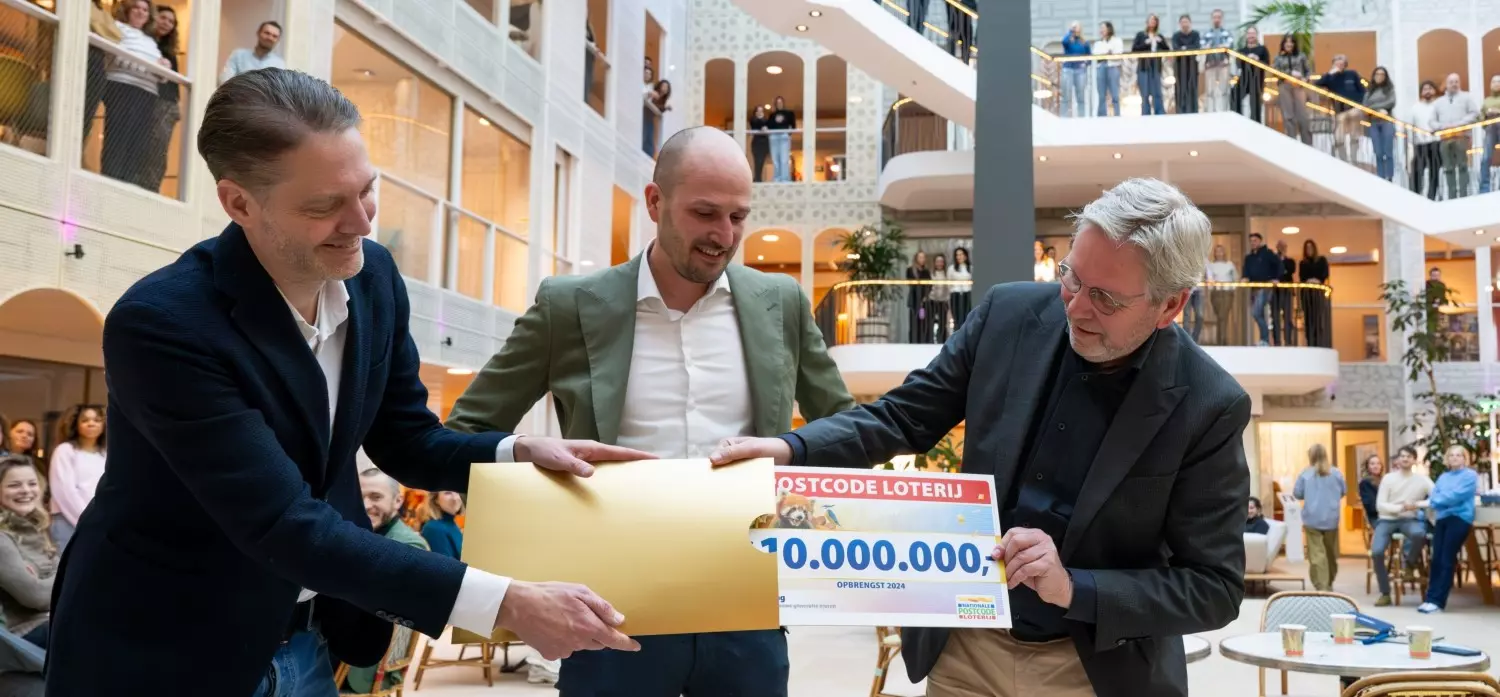 Collega Geert Friebel van de Postcode Loterij verrast de Nierstichting met een cheque van 10 miljoen euro op kantoor.